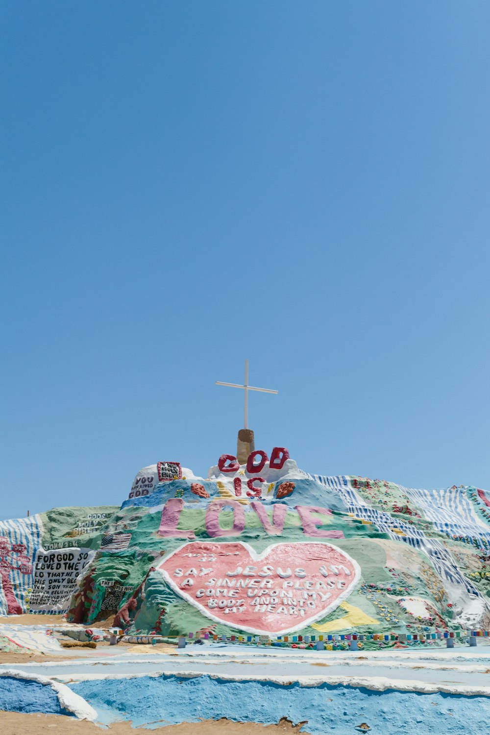 a cross on top of a hill covered in graffiti