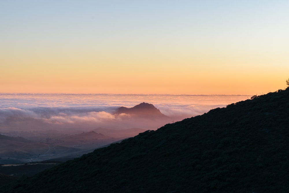 a person standing on top of a hill above the clouds