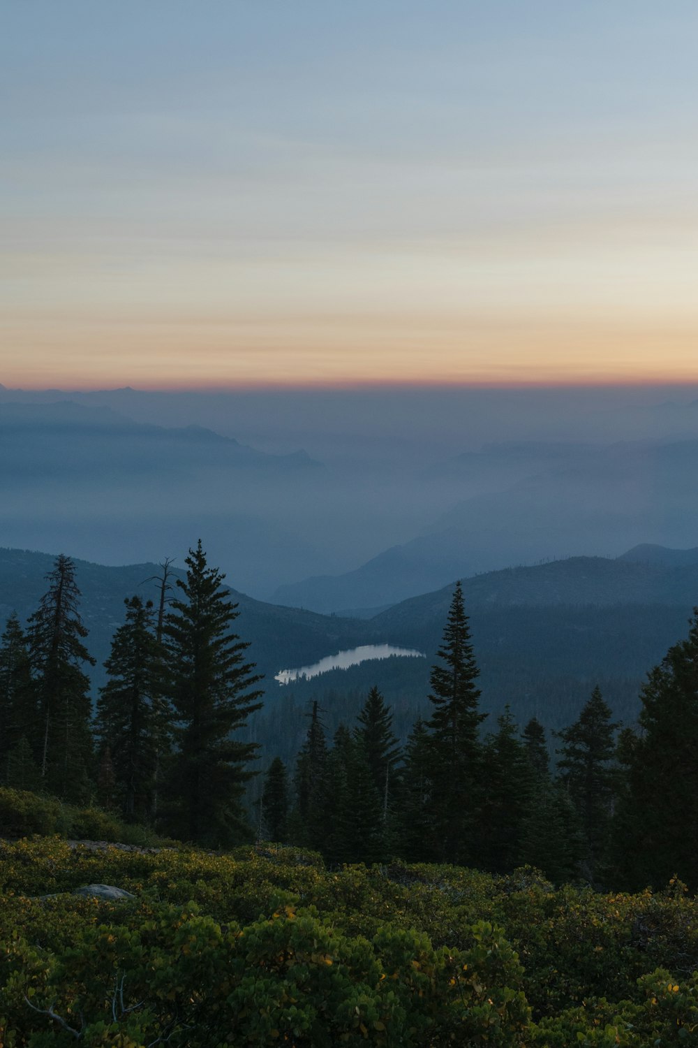 the sun is setting over the mountains and trees