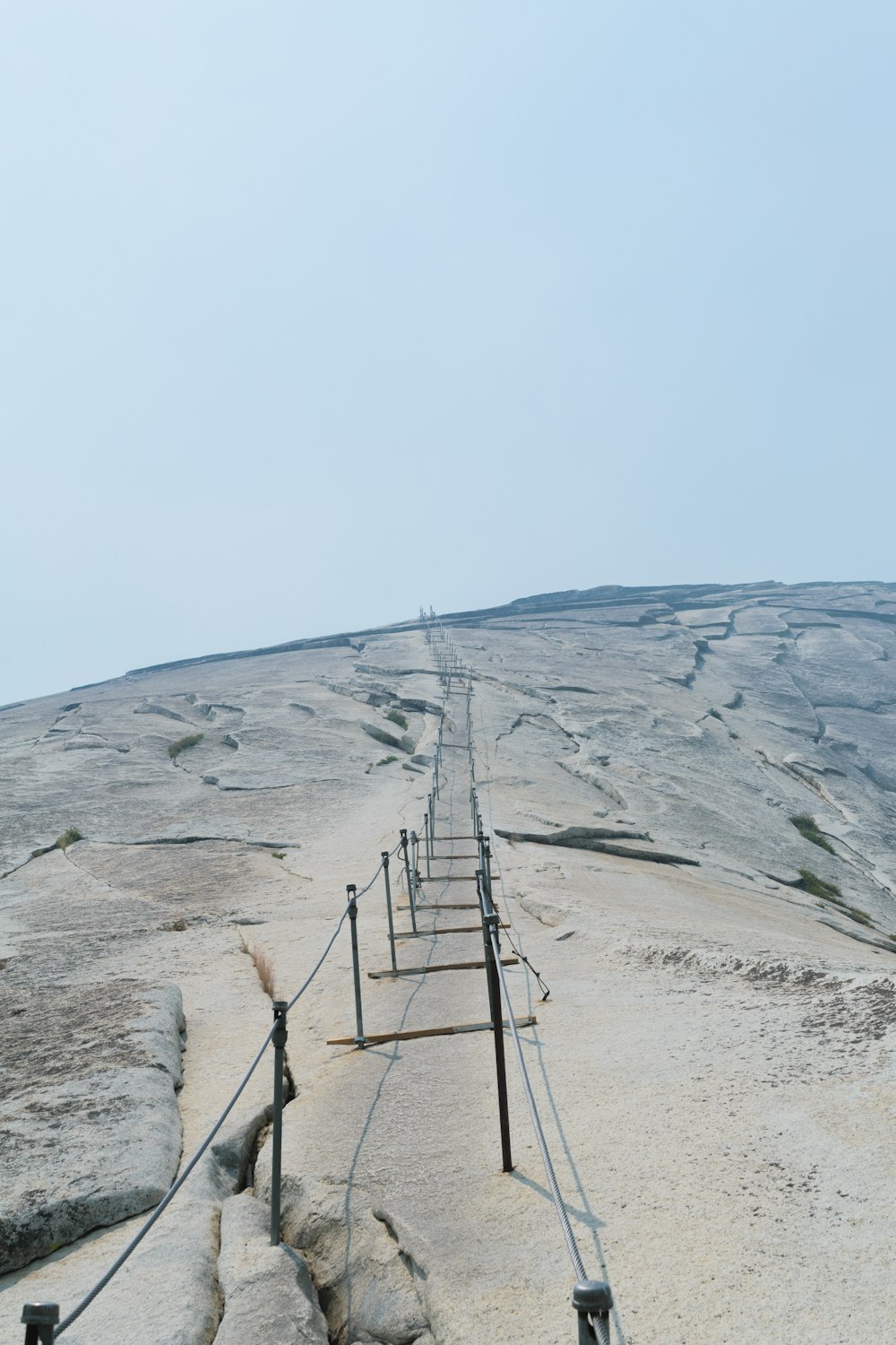 a long metal fence on top of a sandy hill