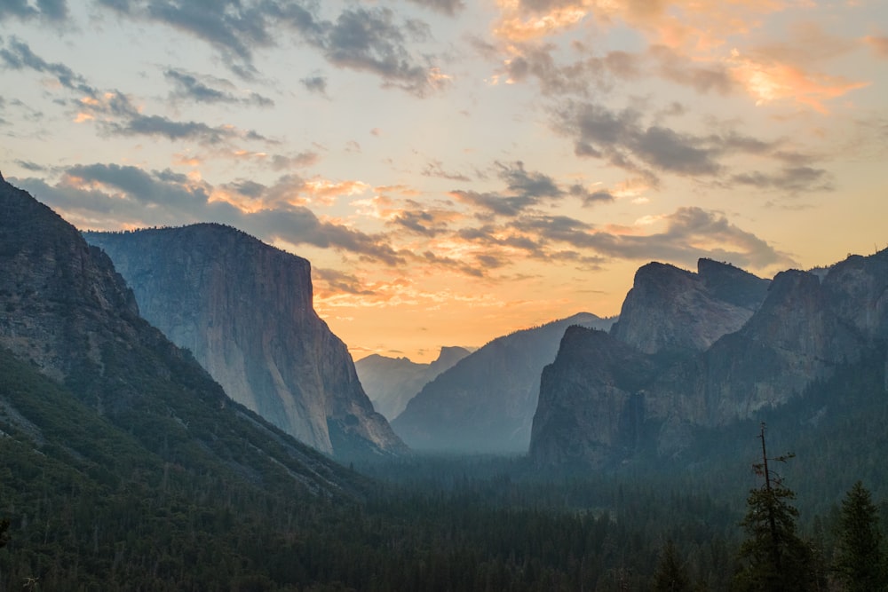 the sun is setting over the mountains in the valley