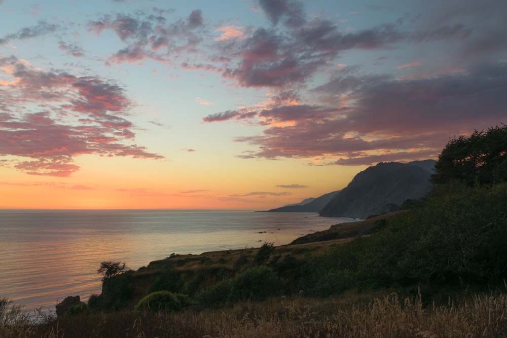 Una vista del atardecer de un cuerpo de agua con montañas al fondo