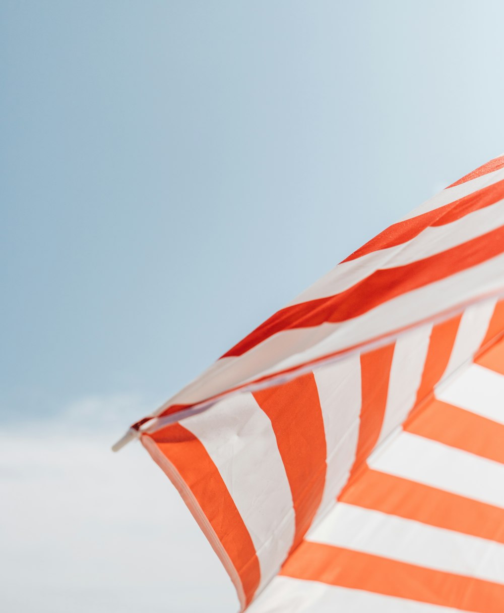 an orange and white striped umbrella flying in the sky