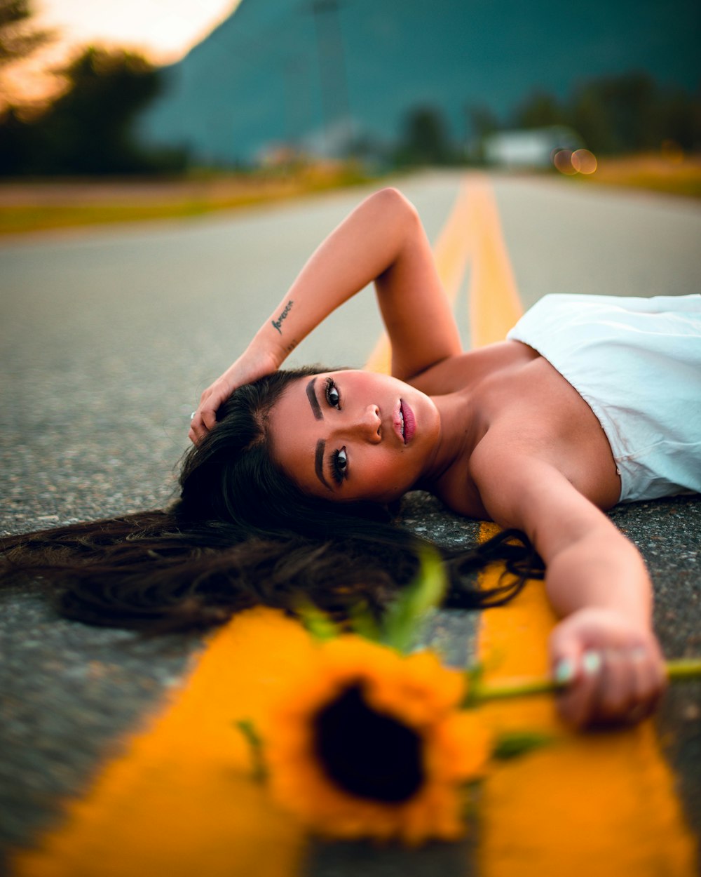 a woman laying on the ground with a flower