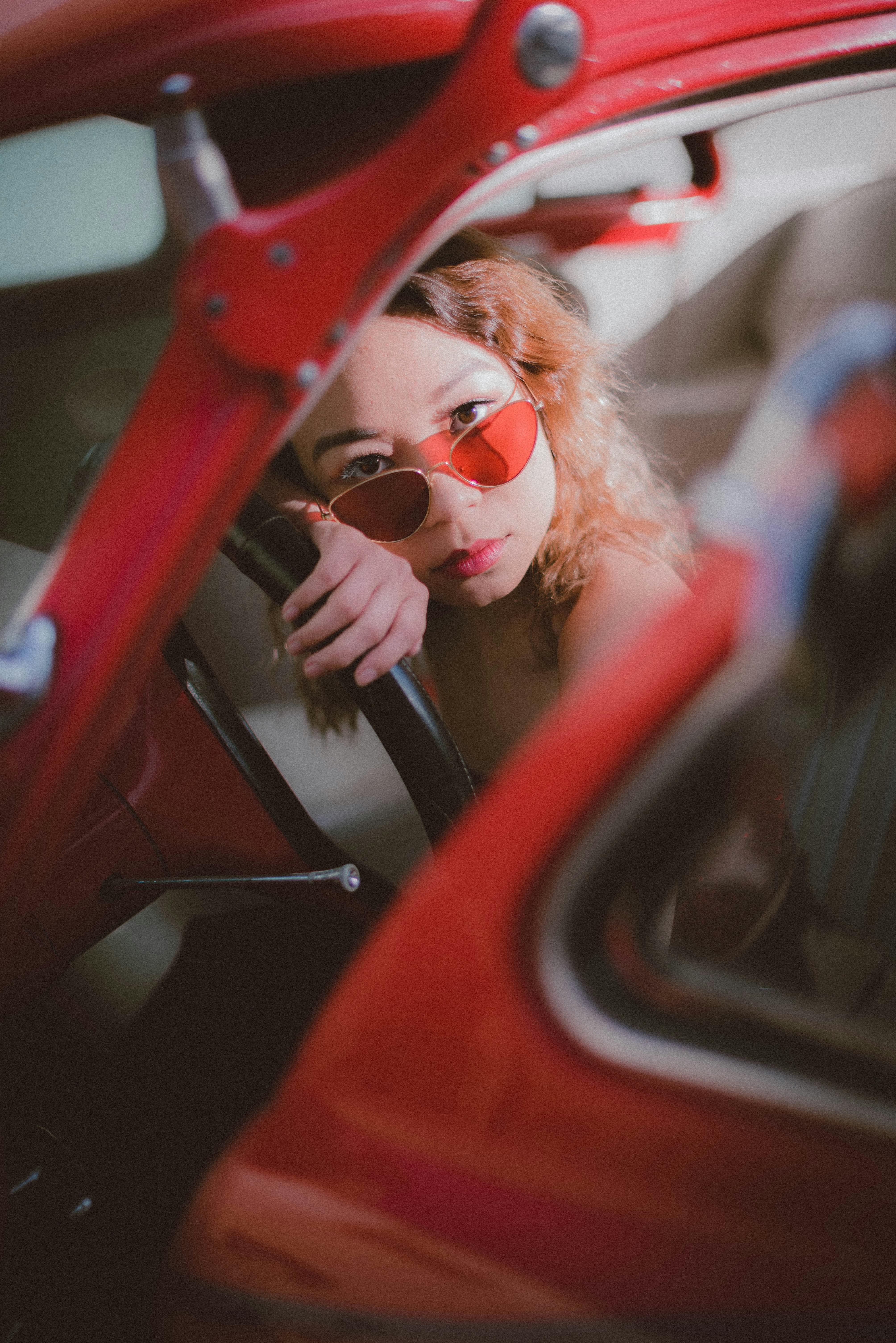 a woman with red sunglasses sitting in a red car