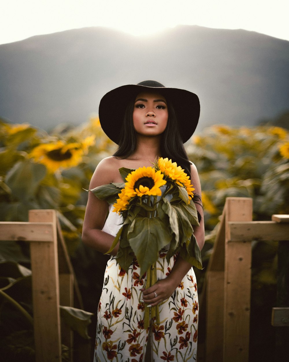 a woman wearing a hat holding a sunflower