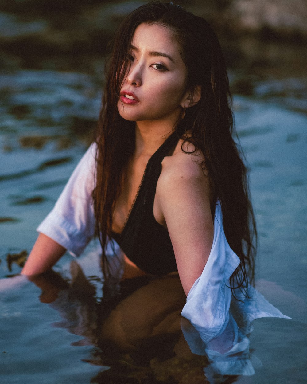 a woman sitting in the water wearing a black and white top