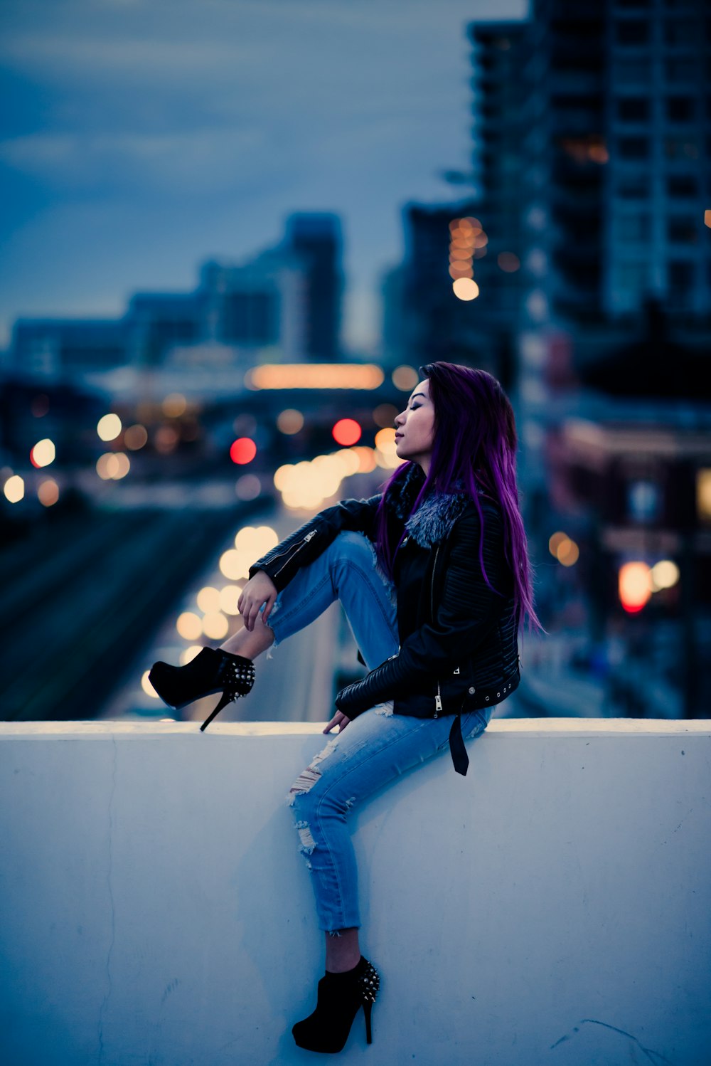 a woman with purple hair sitting on a wall