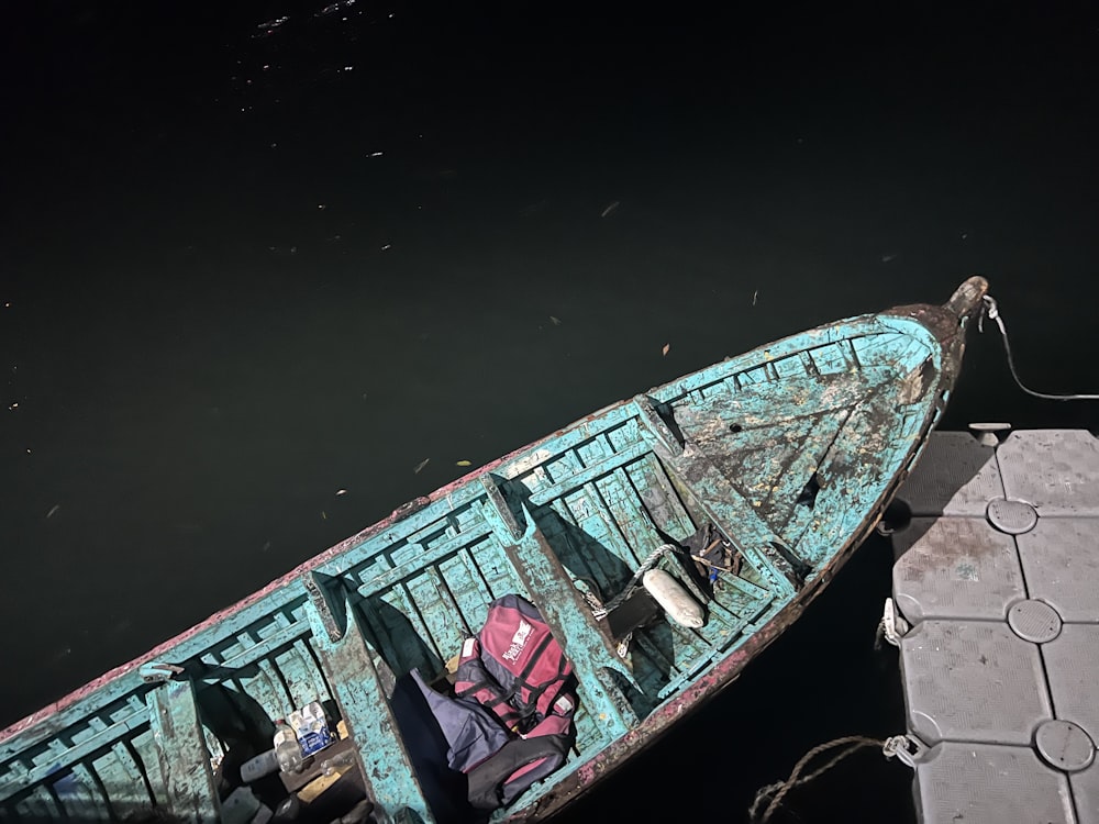 a small blue boat tied to a dock