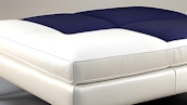 A modern bed with a sleek, minimalist design featuring a padded blue and white mattress. The textures appear soft and comfortable, suggesting luxury and relaxation.