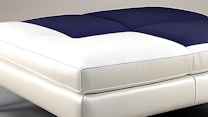 A modern bed with a sleek, minimalist design featuring a padded blue and white mattress. The textures appear soft and comfortable, suggesting luxury and relaxation.