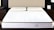 A neatly made bed features a white mattress with two cream-colored pillows. The mattress has a subtle pattern and appears supportive. Situated in a modern bedroom, the bed is flanked by dark wooden nightstands. An elegant, minimalist decor style is evident in the room.
