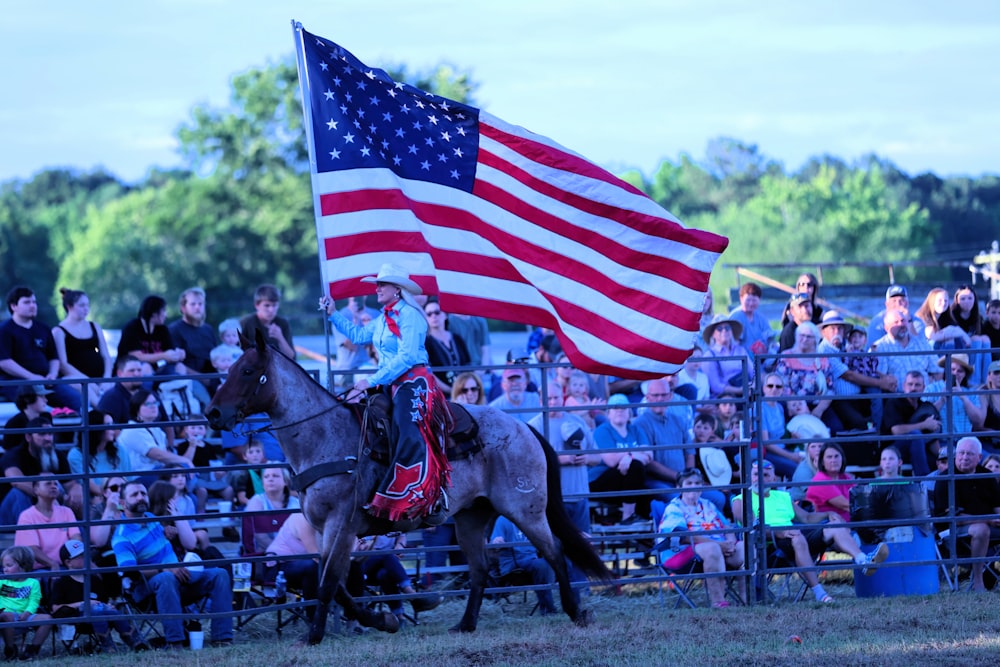 a man riding on the back of a horse holding an american flag