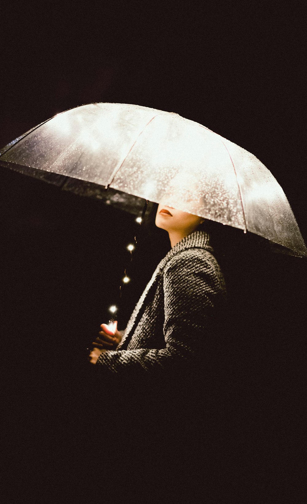 a woman holding an umbrella in the dark