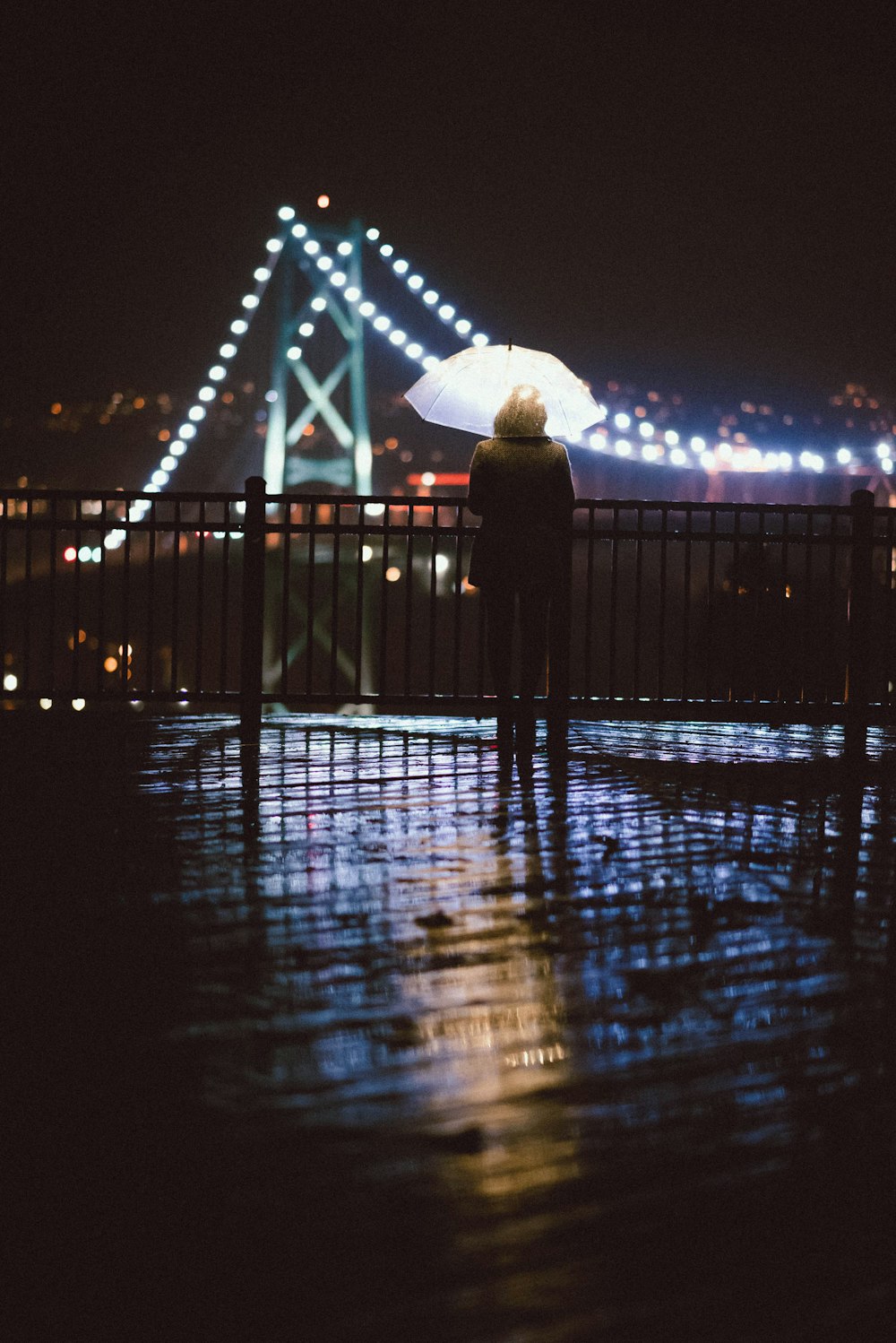 a person standing on a bridge holding an umbrella