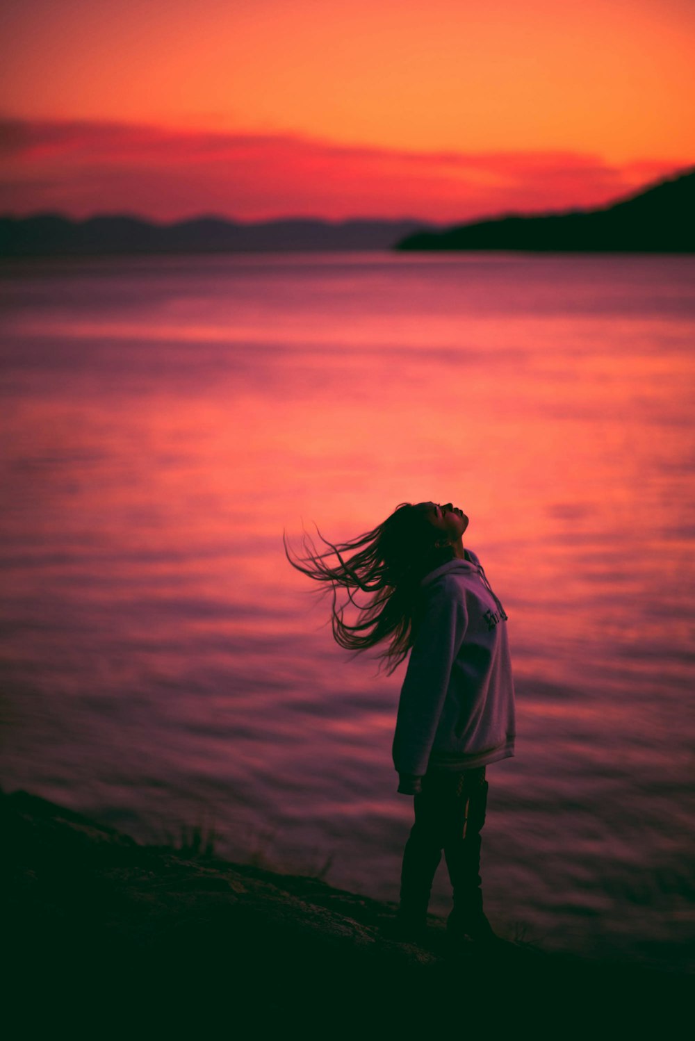 a woman standing on a beach next to a body of water