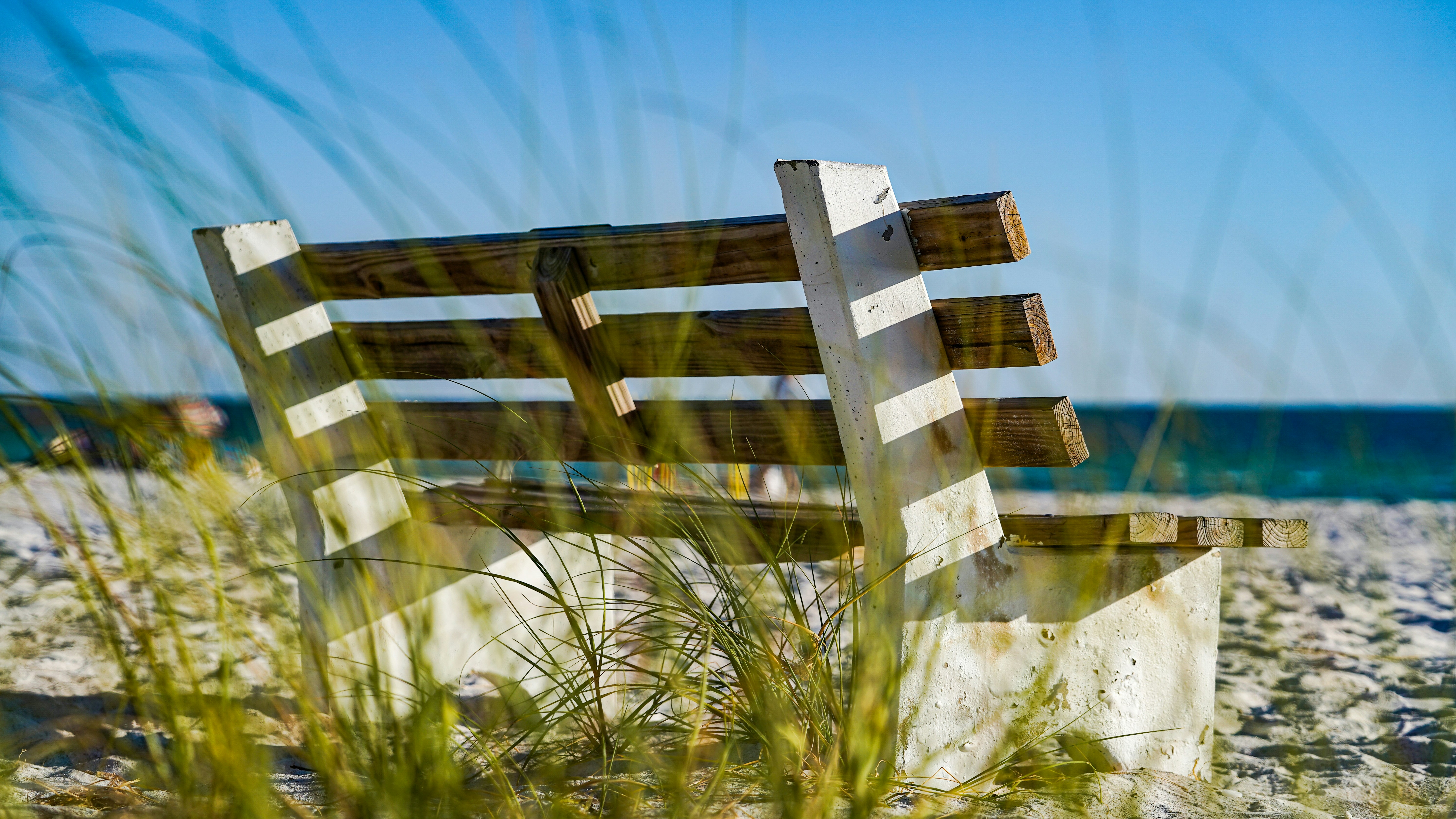 a wooden bench sitting on top of a sandy beach