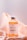 A bottle of vitamin C whitening product is positioned on a peach-colored, silky fabric backdrop. The label on the bottle indicates it contains stem cell ingredients for skin rejuvenation.