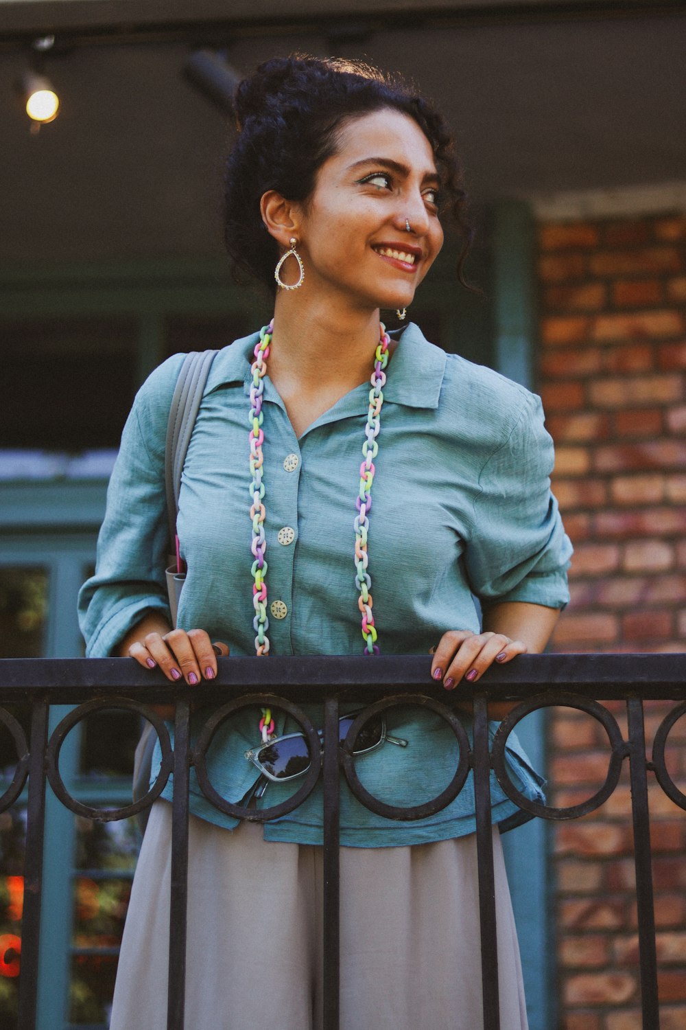 a woman standing on a balcony with a necklace on