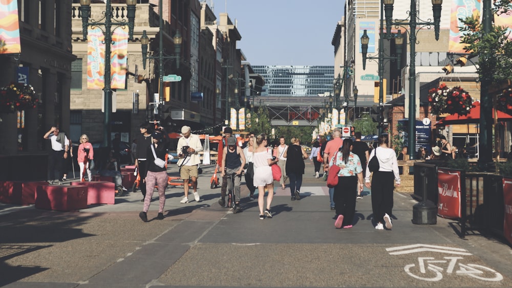 a group of people walking down a street next to tall buildings