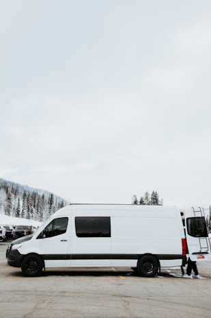 A spacious 8-seater van ready for a group transfer, set against a winter resort backdrop.