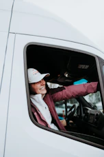 A cheerful teenage student behind the wheel, smiling during a driving lesson.