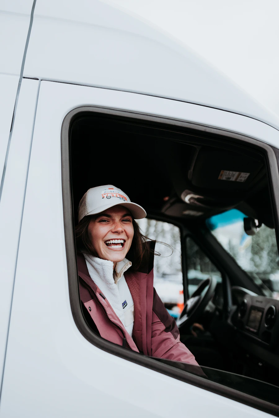 Professional truck driver smiling from the cab of her sleeper truck