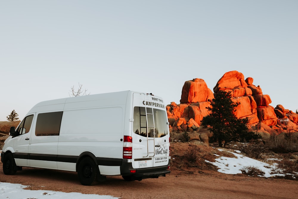 a white van parked in front of a large rock formation