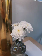 Close-up of a delicate gold-rimmed glass vase with fresh white flowers on a marble surface