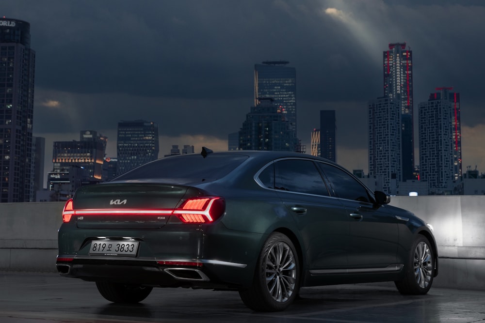 a black car parked in front of a city skyline