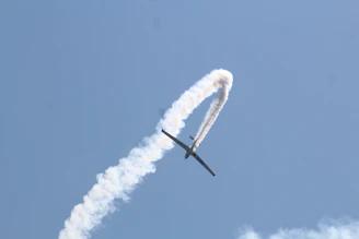 A dynamic shot of an airshow plane performing a loop, trails of smoke tracing its path against a deep blue sky.