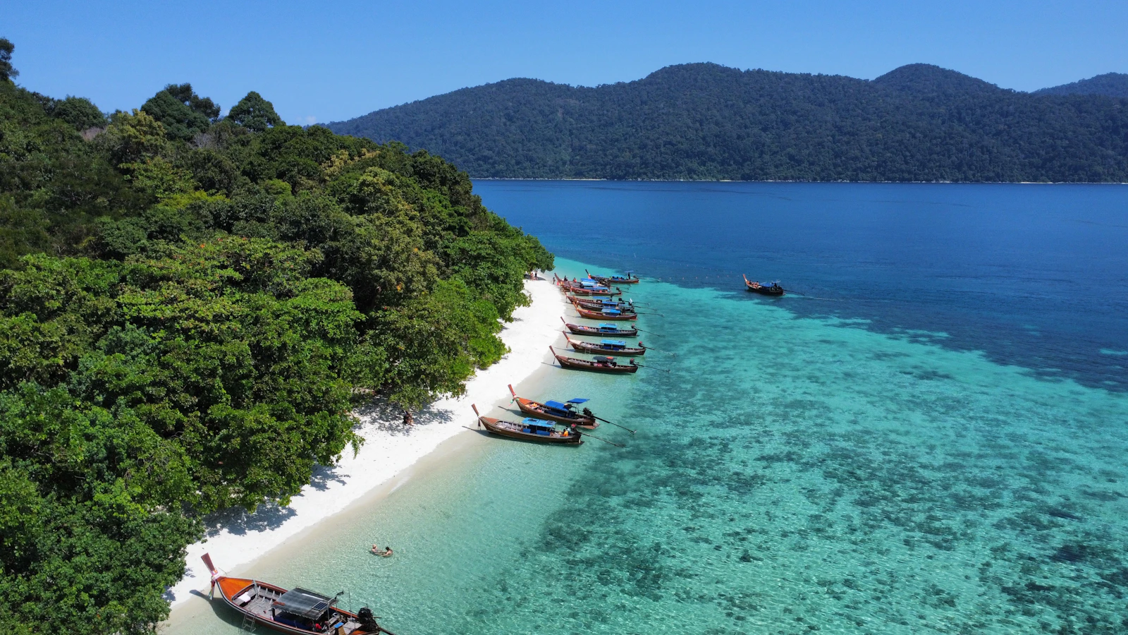 Longtail boats on a white-sand beach with turquoise water in the Andaman Sea, Thailand