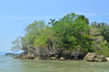 Lush green island with white sandy shores and gentle waves lapping the coast