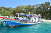 A colorful boat docked by a crystal-clear lagoon surrounded by lush greenery.