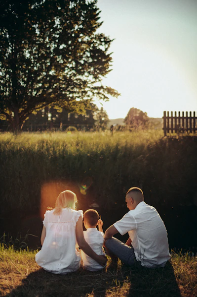 a man and a woman sitting on the ground next to a child