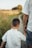 A child and an adult are walking hand in hand along a path surrounded by grass. They are dressed in casual summer clothing, and the image is taken from behind, focusing on their close bond.