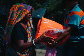 An elderly woman receiving a warm blanket and care package from a volunteer.