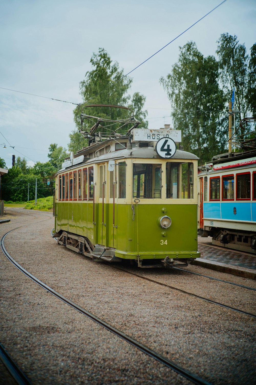 a green trolley car sitting on the tracks