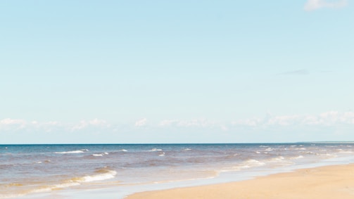 A serene beach with calm waves under a clear sky