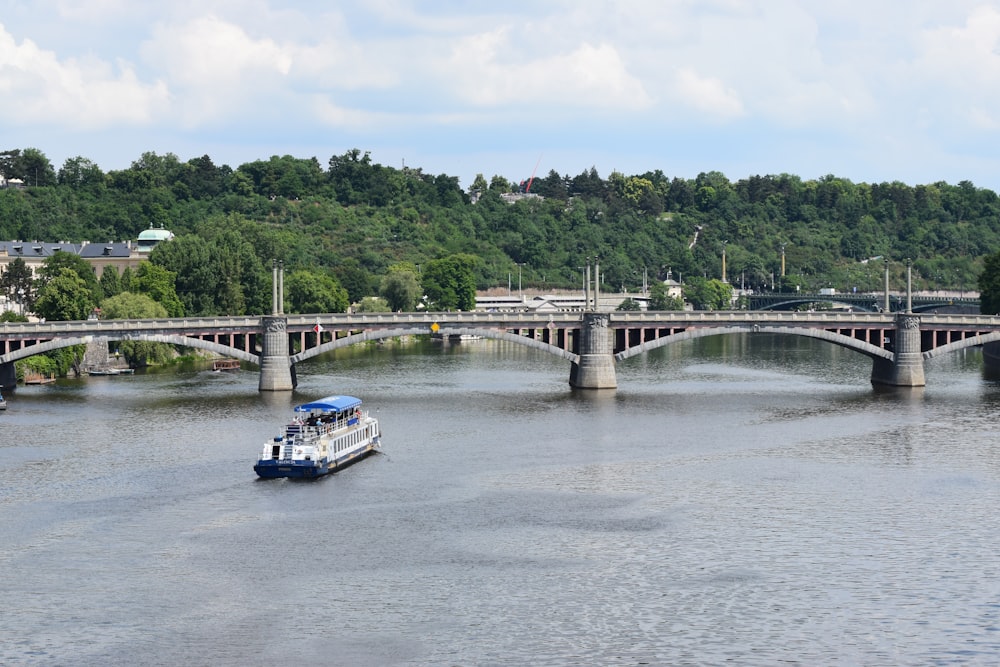 a boat traveling down a river under a bridge