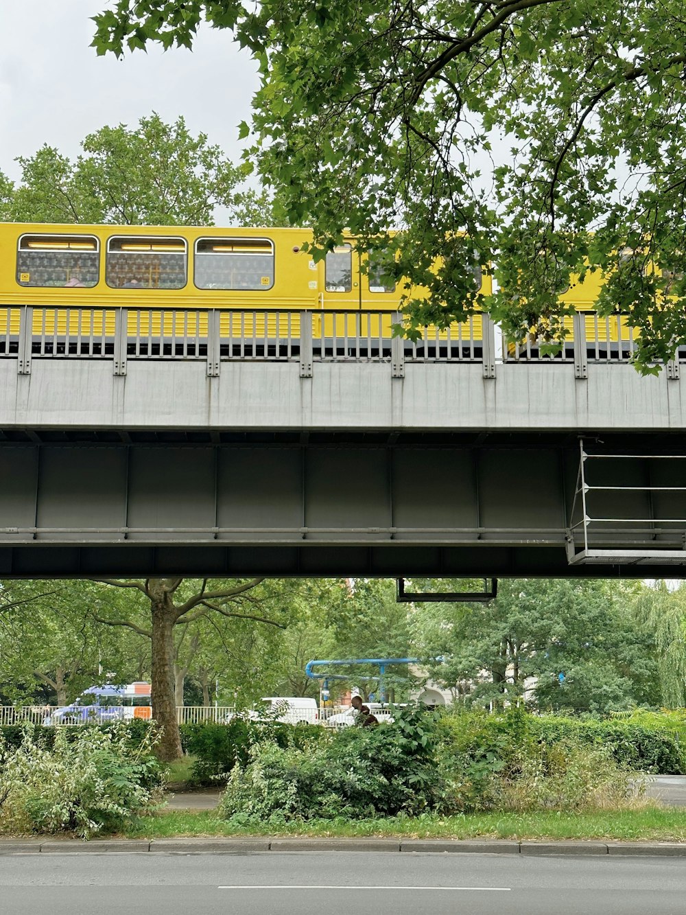 a yellow train traveling over a bridge over a street