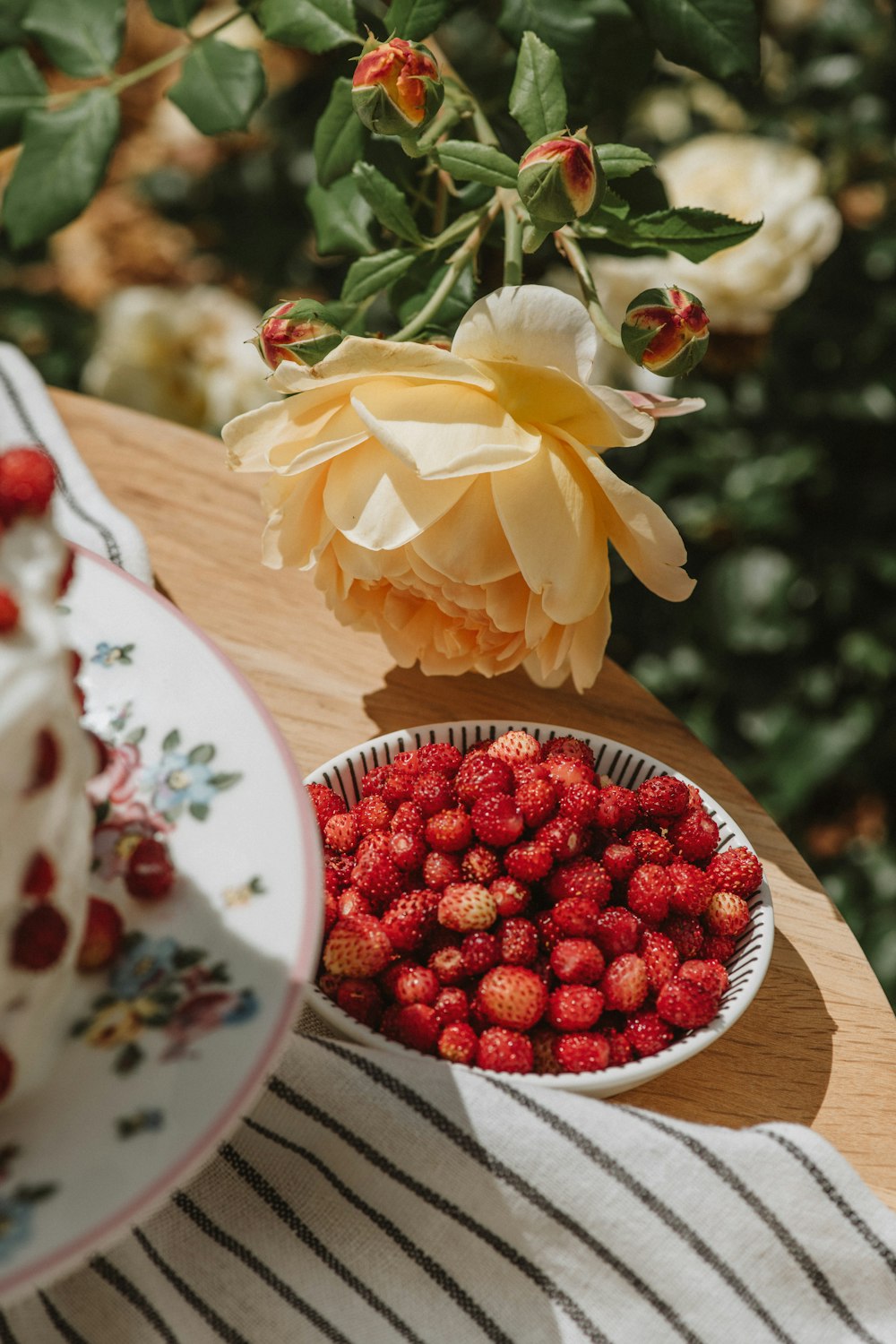 a plate of strawberries next to a bowl of strawberries