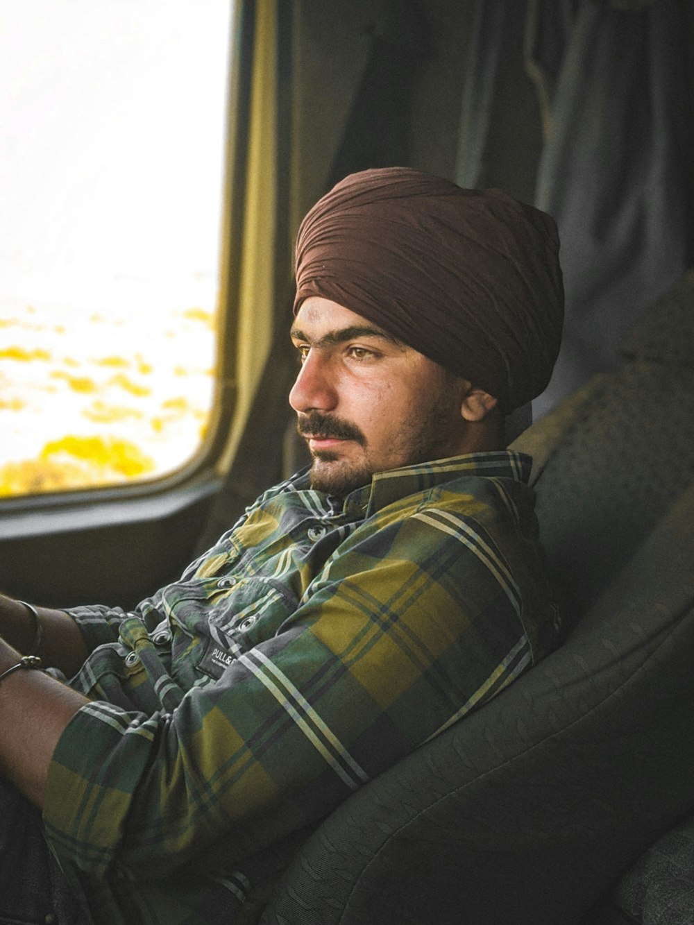 a man in a turban sitting on a plane looking out the window