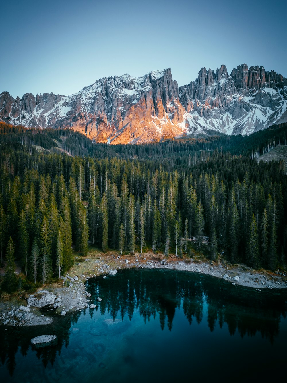 a mountain range with a lake surrounded by trees