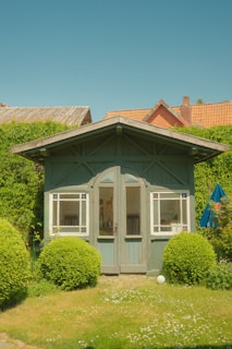 A sturdy steel-frame garden shed with wood-like metal panels under a bright blue sky.