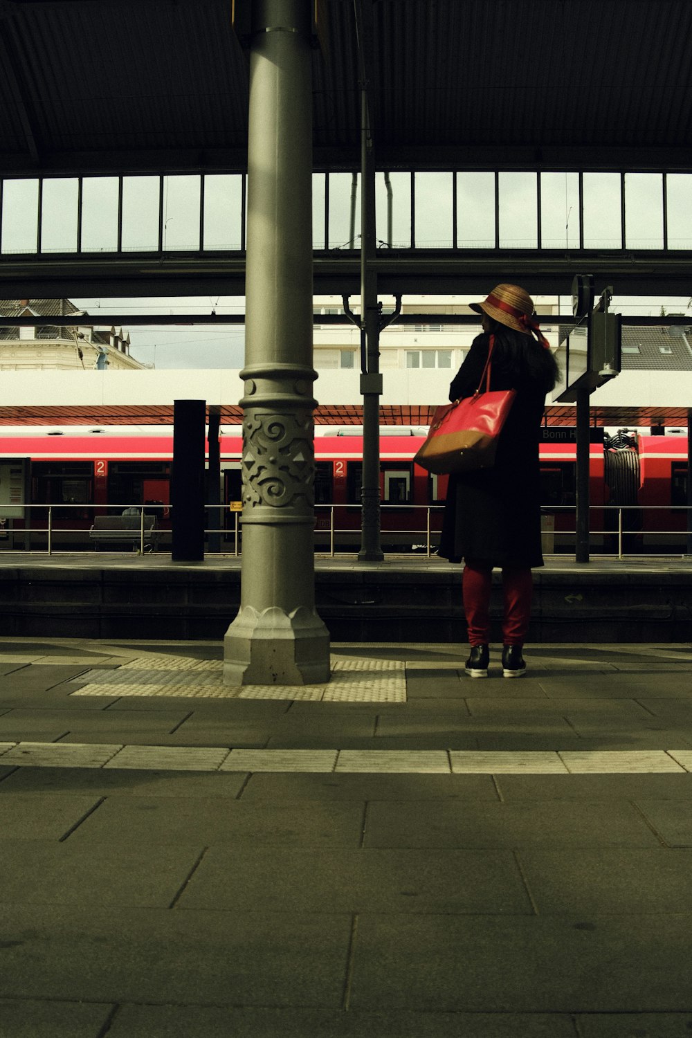 a woman standing on a platform with a red bag