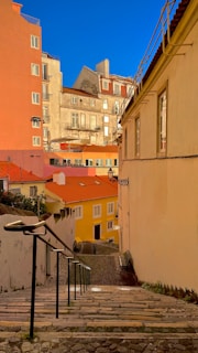 A winding cobblestone street lined with charming pastel-colored houses under soft sunlight.
