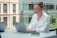 Smiling professional using a laptop in a modern office environment.