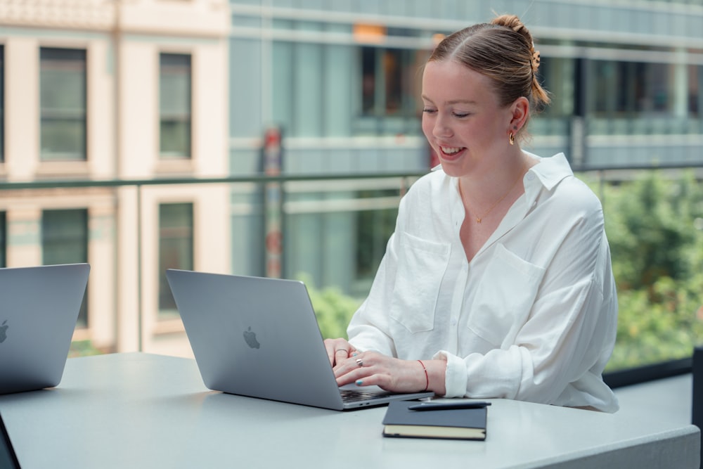 a woman sitting at a table using a laptop computer