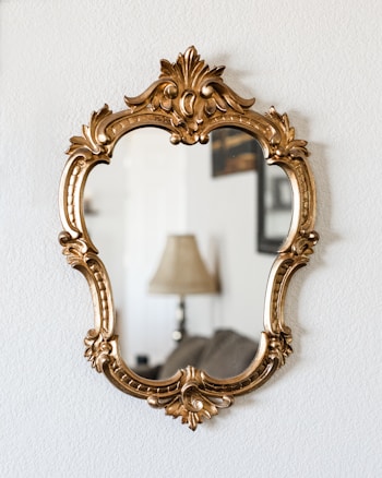 a mirror hanging on a wall next to a lamp